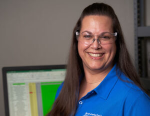 Female worker in manufacturing plant at computer smiling